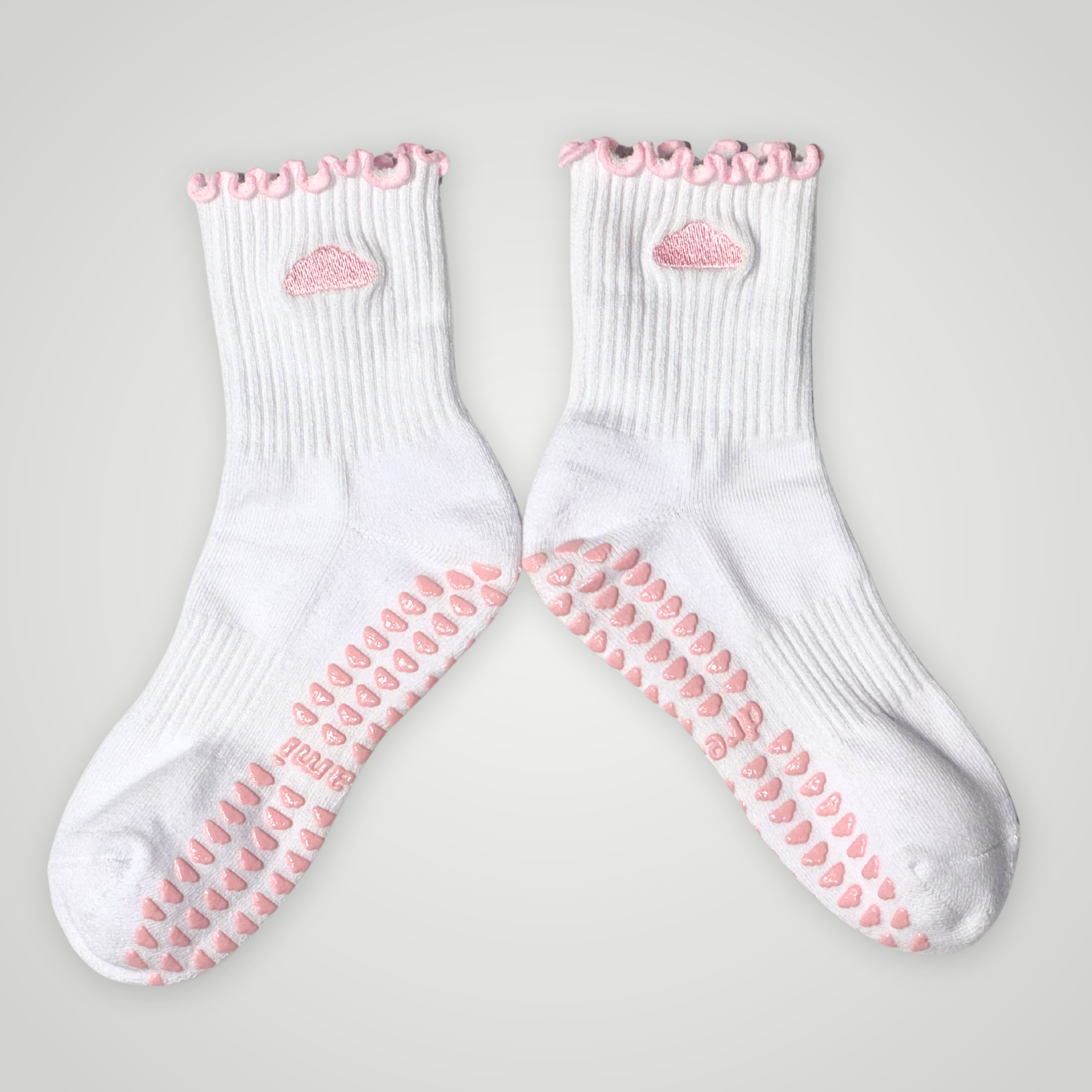 White socks with pink cloud design and grips on gray background