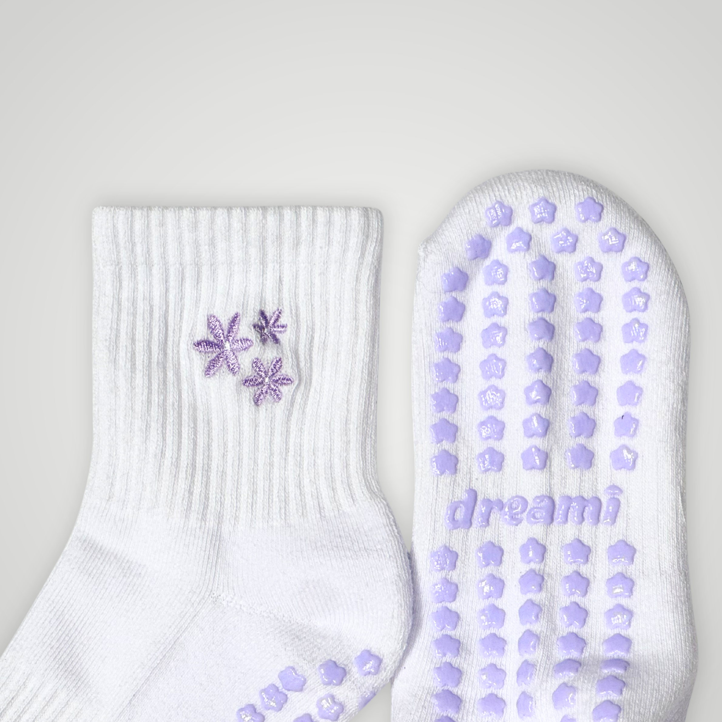Close up of white socks with purple flower design and grips