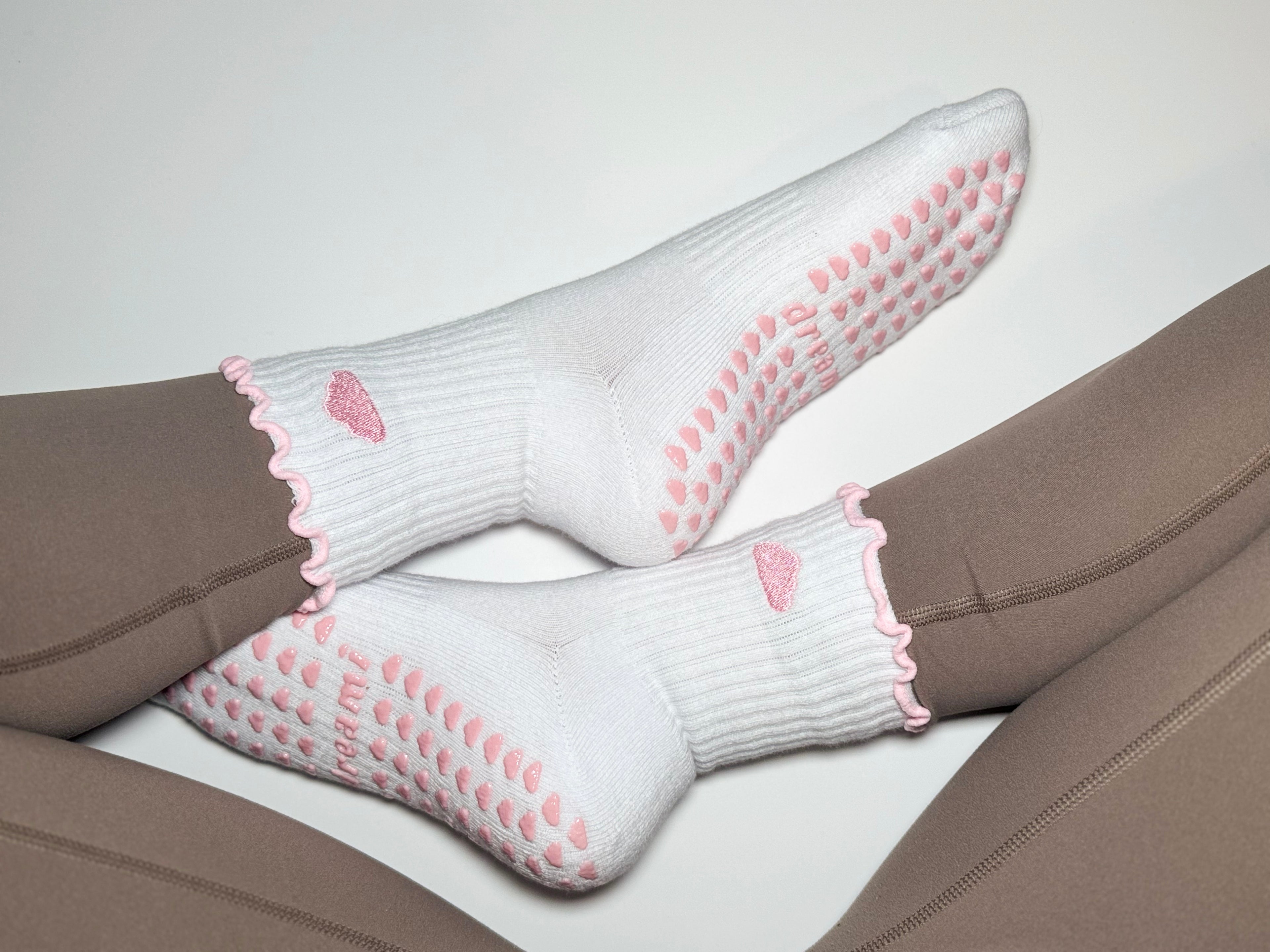 White socks with pink cloud design and grips on person wearing brown leggings