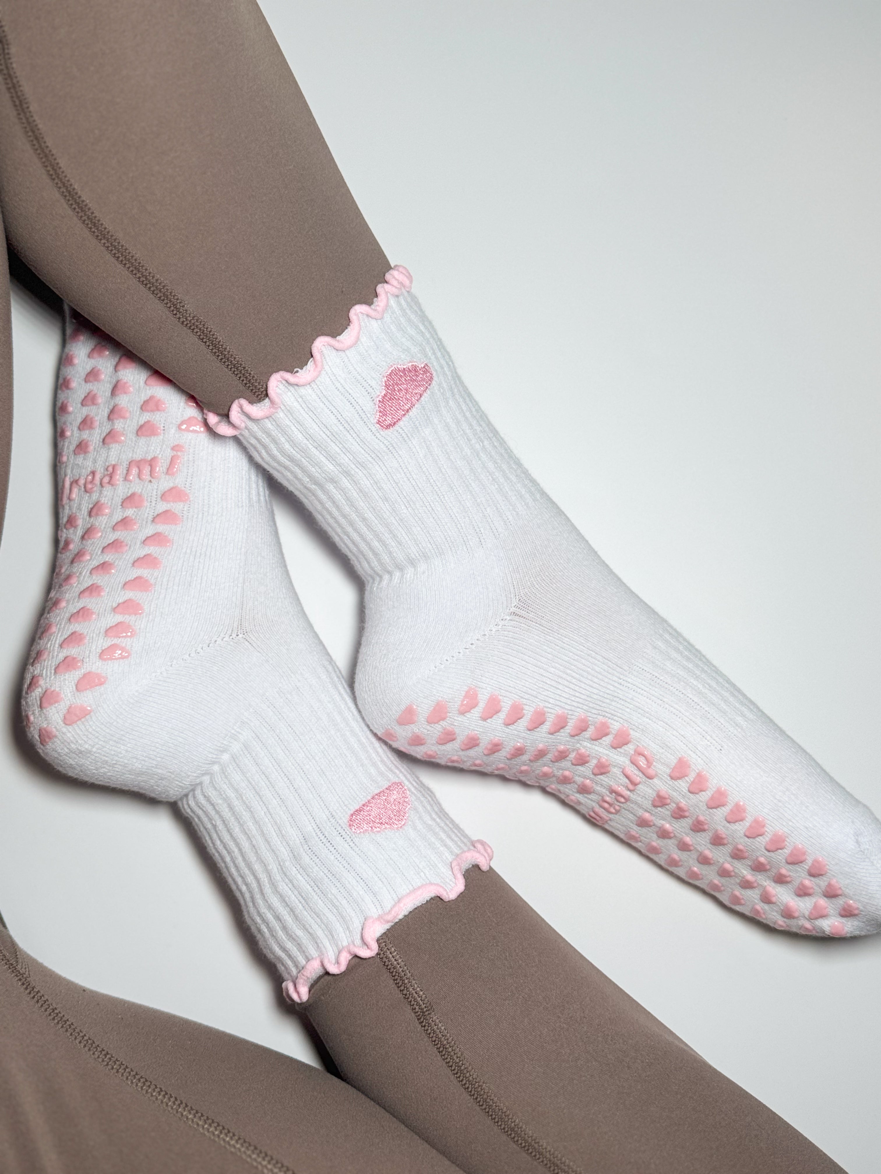White socks with pink cloud design and grips on person wearing brown leggings
