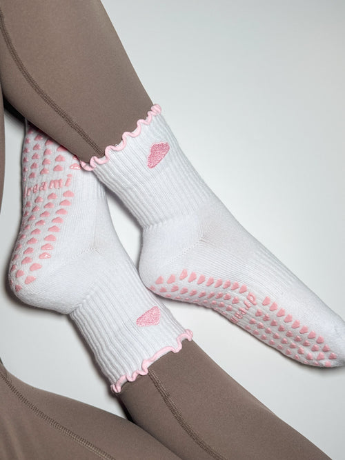 White socks with pink cloud design and grips on person wearing brown leggings
