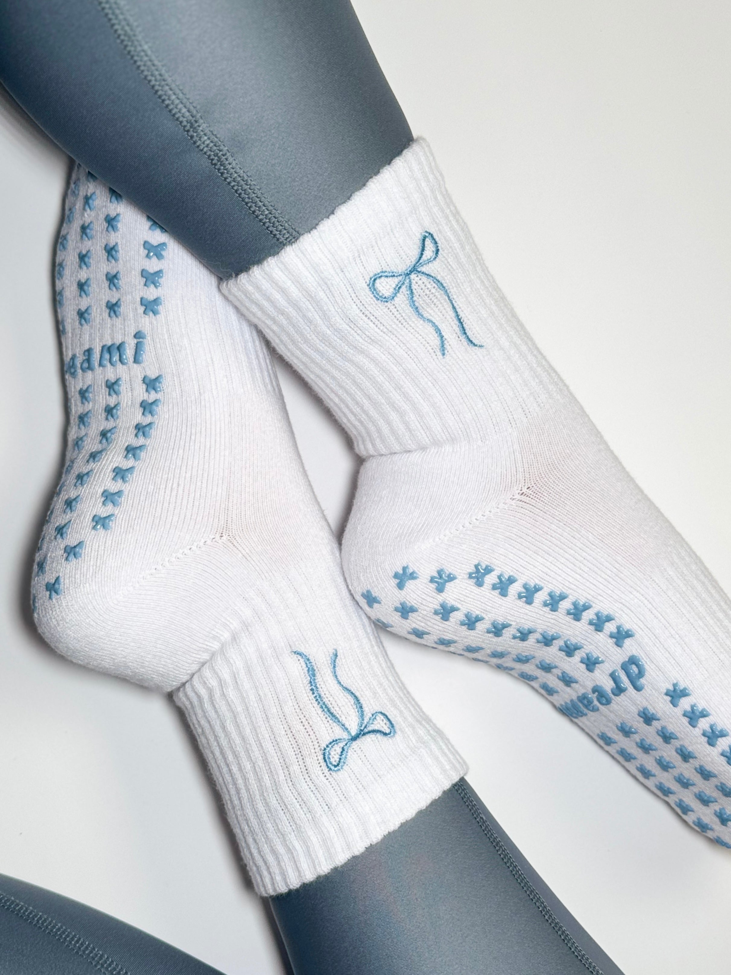 White socks with blue bow design and bow grips on person wearing blue leggings
