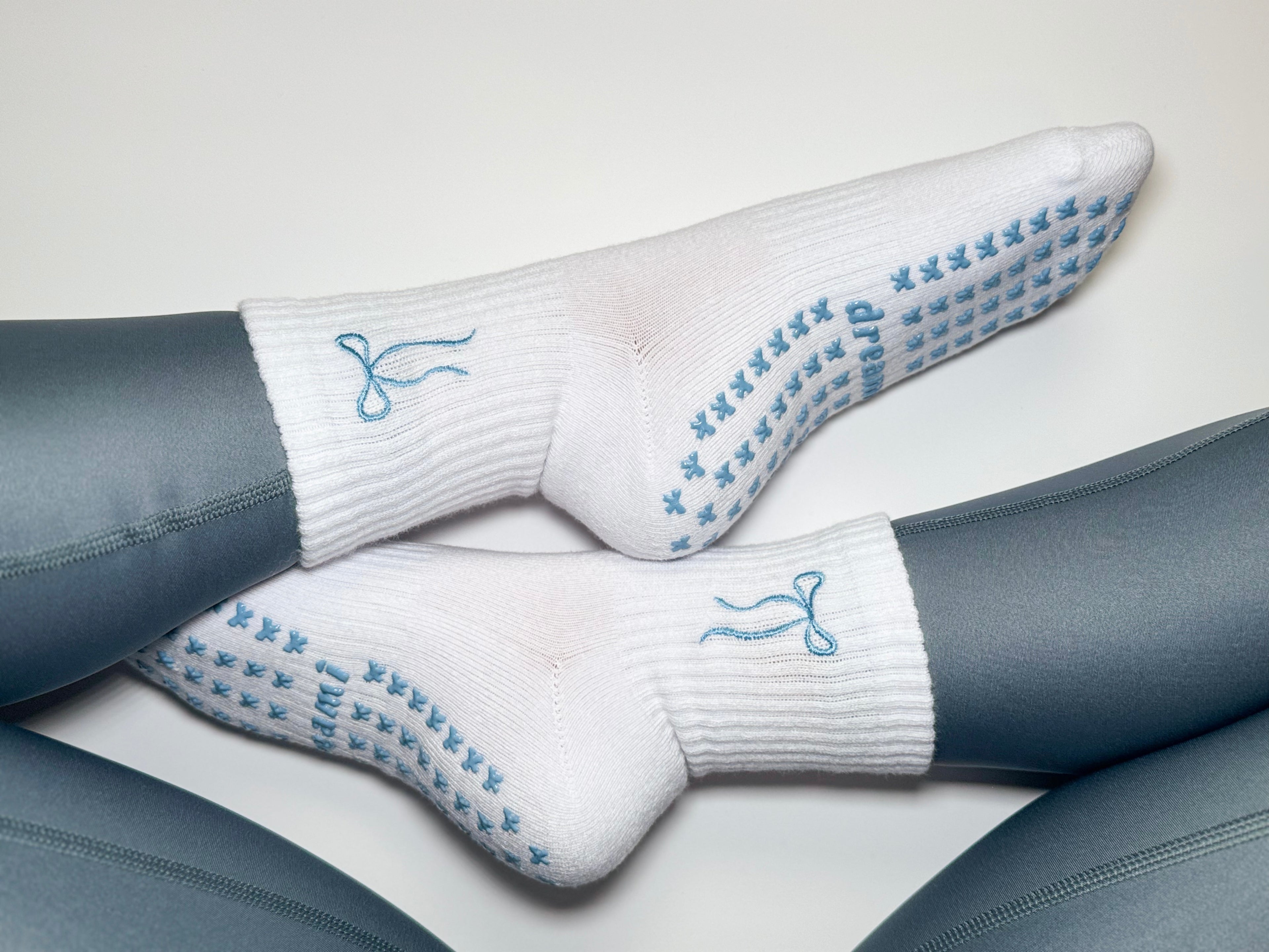 White socks with blue bow design and bow grips on person wearing blue leggings