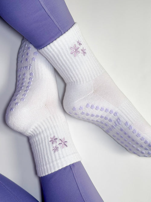 White socks with purple flower design and grips on person wearing purple leggings