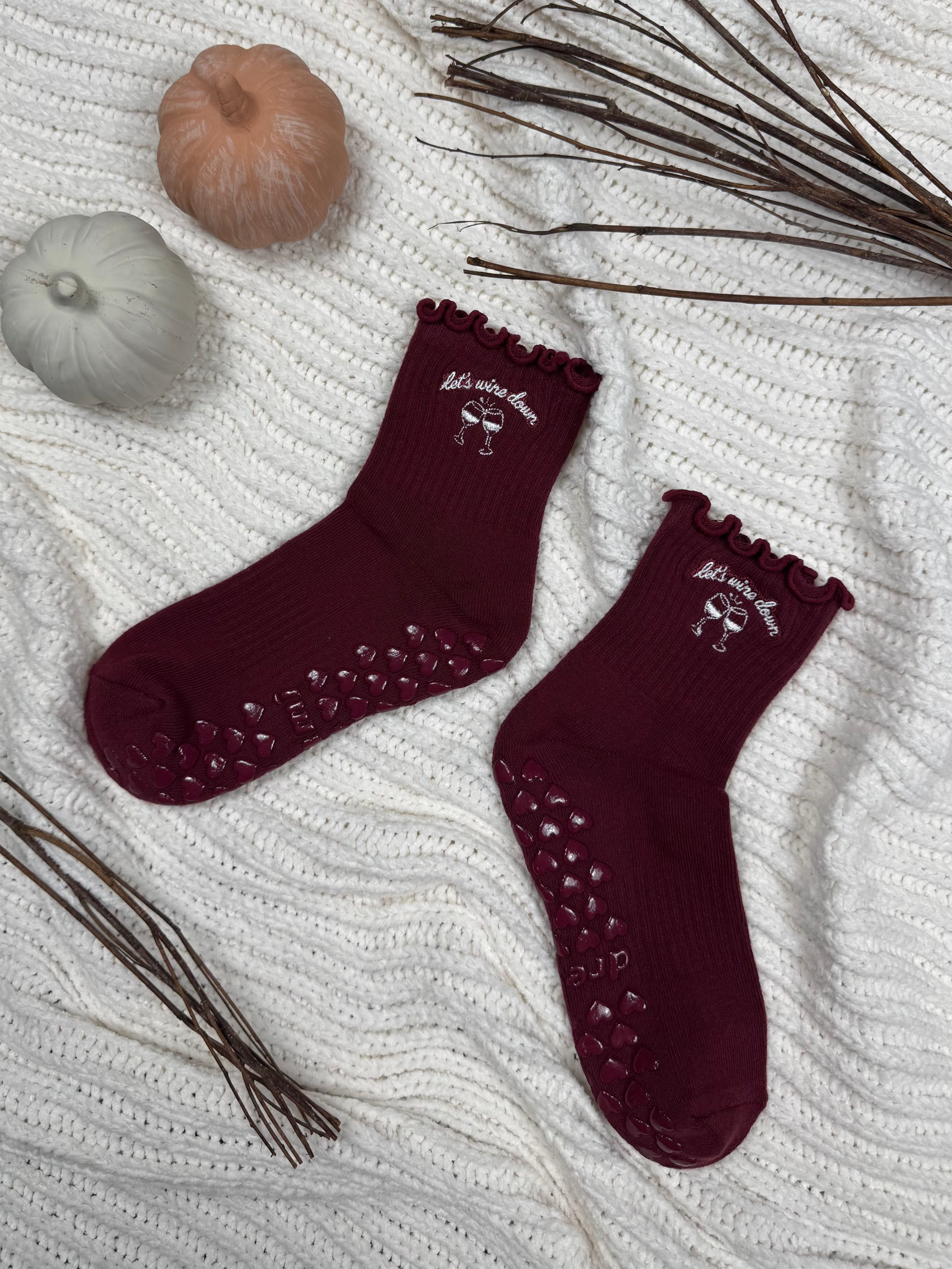Wine red colored grip socks with "let's wine down" embroidered design