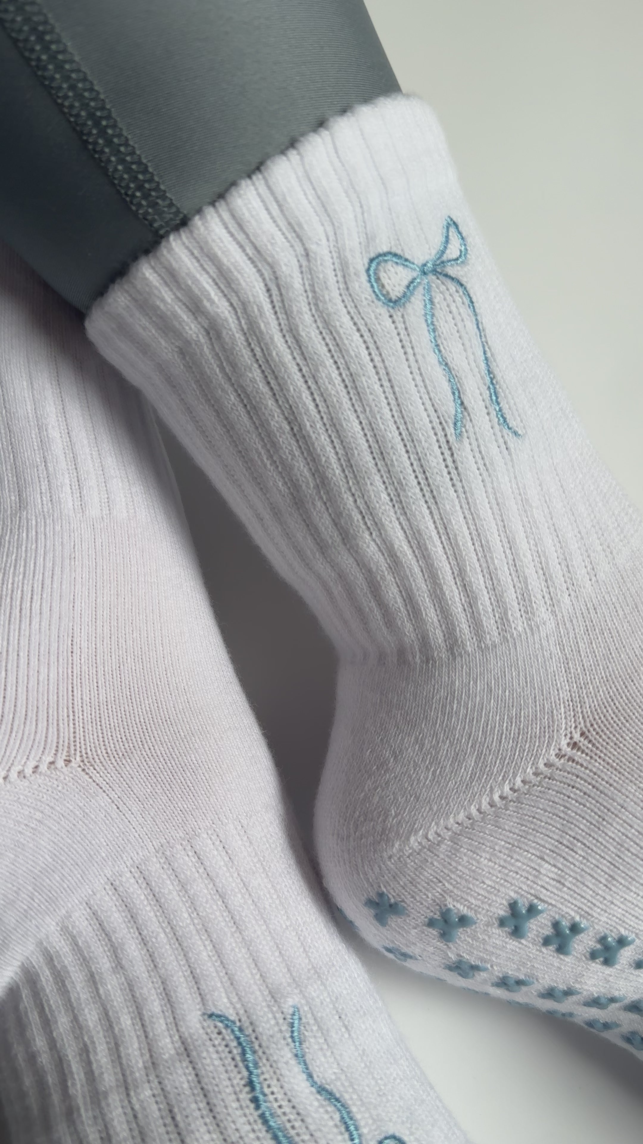 Video of white socks with blue bow design and bow grips on person wearing blue leggings