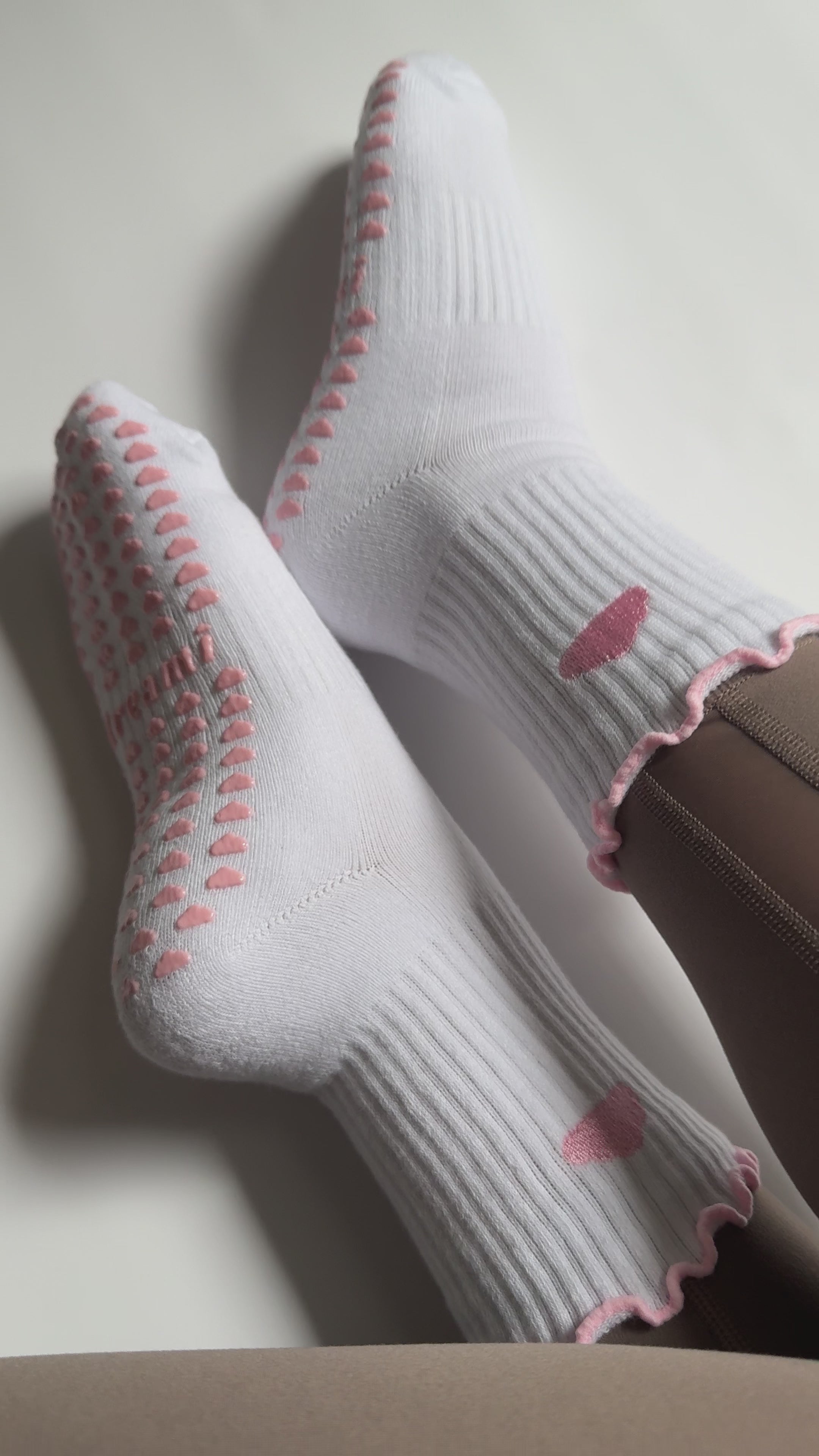 Video of white socks with pink cloud design and grips on person wearing brown leggings