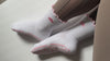 Video of white socks with pink cloud design and grips on person wearing brown leggings
